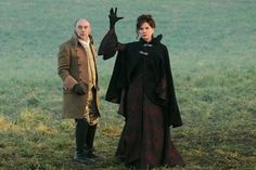 two people standing in a field with one holding his hand up