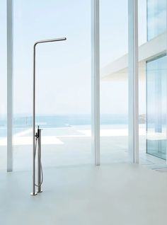 a modern shower head in the middle of an empty room with large windows and ocean view