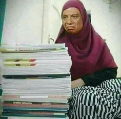 a woman sitting on the floor with stacks of papers in front of her and looking at the camera