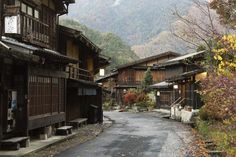 an old street in the mountainside town with wooden buildings and autumn leaves on the trees