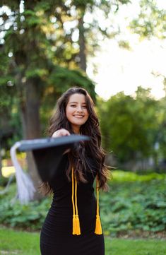 a woman in a black dress holding a frisbee and smiling at the camera