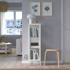 a white book shelf with books on it in front of a living room door and window