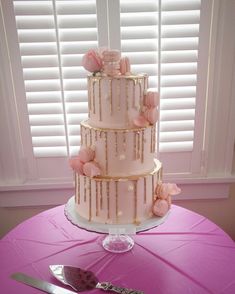 a three tiered cake sitting on top of a table next to a knife and fork