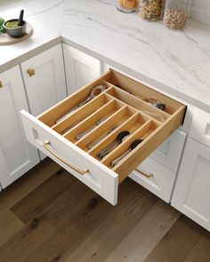 an open drawer in the middle of a kitchen with utensils and spoons