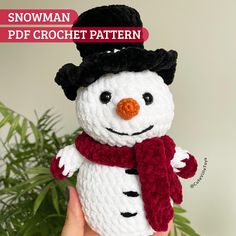 a crocheted snowman is wearing a red scarf and black hat with orange nose