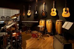 a room with guitars, drums and musical equipment on the wall next to each other