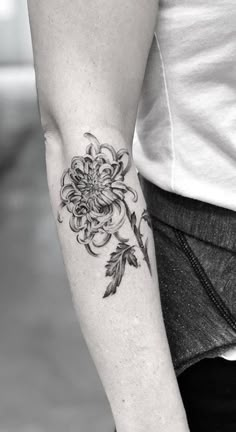 a black and white photo of a woman's arm with a flower tattoo on it