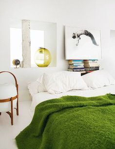 a bedroom with a green blanket on the bed and a chair in front of it