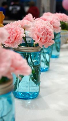 pink carnations in mason jars lined up on a table