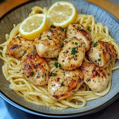 some chicken and noodles with lemon wedges on the side