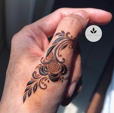 a woman's hand with a henna tattoo on her left wrist and finger