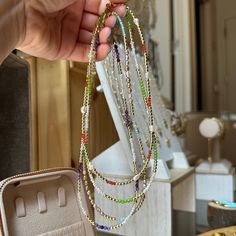 a person holding some beads in front of a jewelry box with other items on it