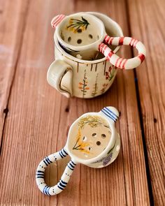 two coffee mugs sitting on top of a wooden table next to candy canes