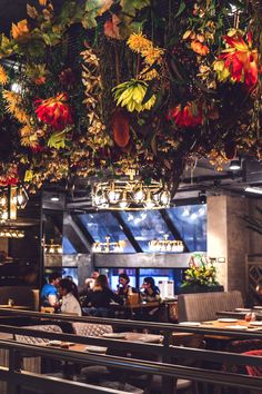 the restaurant is decorated with flowers and chandeliers hanging from the ceiling over the tables