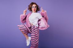 a woman in pink and black striped pants posing for the camera with her hands up