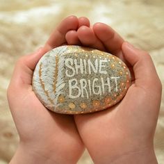 someone holding a rock with the words shine bright written on it