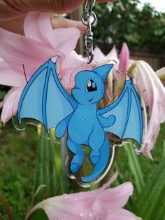 a blue dragon keychain hanging from a pink flower