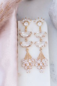 three pairs of earrings on top of a white marble slab with pink furnishing