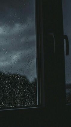 a window with rain drops on it and a butterfly flying in the air next to it