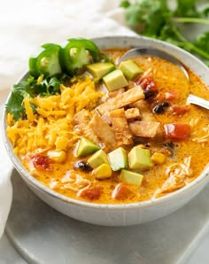 a white bowl filled with chicken, rice and veggie soup on top of a table