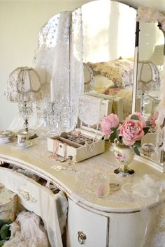 a white dresser topped with a mirror next to a pink rose