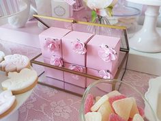 pink boxes filled with candy sitting on top of a table next to other desserts