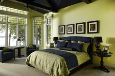 a bed room with a neatly made bed next to two chairs and a table in front of a large window