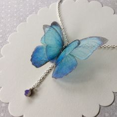 I'm in love with blue Morpho butterflies and Opals. This is a delicate and dainty creation, that celebrate my love for them. The silk organza butterfly measure about 5 cm wingspan. Silver Plated 925 chain is available in 40 cm (16 inches), 45 cm (18 inches) or more, you can choose! Closed with lobster clasp. Nickel free. The necklace pictured is long 40 cm (16 inches) and it's already sold. The pendant is a natural raw polished BLUE and GREEN Ethiopian Welo Opal that measures about 4 mm and is a Blue Butterfly Necklace For Gifts, Blue Butterfly Necklace For Gift, Elegant Blue Butterfly Charm Necklace, Elegant Blue Butterfly Necklace With Charm, Adjustable Butterfly Necklace For Gift, Blue Jewelry With Butterfly Charm For Jewelry Making, Handmade Blue Butterfly Necklace, Dainty Blue Butterfly Jewelry, Whimsical Blue Necklace For Gifts