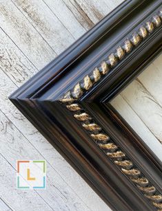 an ornate black frame with gold trim on a white wooden background, showing the intricate design