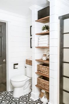 a white toilet sitting in a bathroom next to a wooden shelf