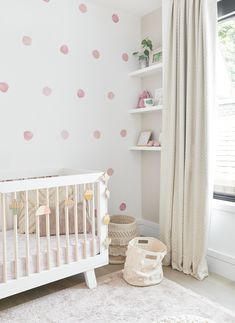 a baby's room with pink polka dots on the wall and white crib