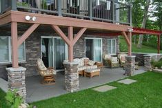 an outside patio with chairs and tables in the grass next to a building that has two balconies on top of it