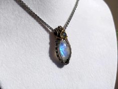 Elevate your style with this stunning handcrafted wire wrapped necklace featuring a shimmering blue Moonstone and a petite green Labradorite. The intricate wire wrapping is crafted using German silver and brass wire, adding a touch of elegance to the design. Measuring approximately 2x4 cm, this necklace hangs beautifully on a silver snake chain, creating a chic and timeless look. It makes a perfect gift for Mother's Day or any special occasion. Ready to ship with free shipping included. Materials: - Blue Moonstone - Green Labradorite - German Silver Wire - Brass Wire - Silver Snake Chain 45 cm  Dimensions: Pendant Size: Approximately 2x4 cm White Labradorite Necklace As Gift, White Labradorite Necklace For Gift, Daily Wear Necklace, Labradorite Gemstone Jewelry, Green Labradorite, Jewelry Elegant, Wrapped Necklace, Wear Necklaces, Blue Moonstone