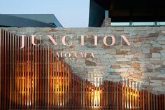 a stone wall with the word junction now on it and wooden slats behind it