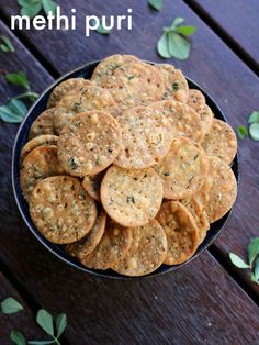 a bowl filled with crackers sitting on top of a wooden table next to green leaves