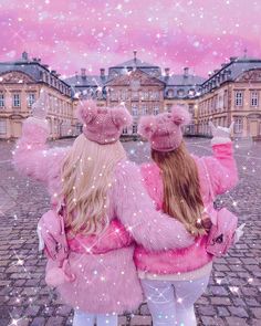 two girls in pink jackets and hats are looking at the sky with sparkles all around them