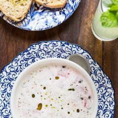 a bowl of soup on a blue and white plate next to a glass of milk