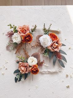 an arrangement of flowers arranged on top of a piece of paper with leaves and twigs