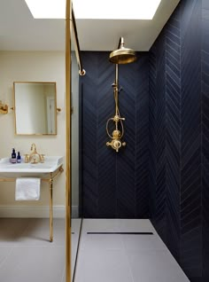 a bathroom with a shower, sink and mirror in the corner on the wall next to it is a gold faucet