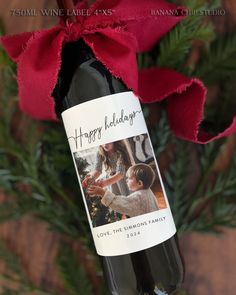 a bottle of wine with a red ribbon around it and a christmas tree in the background