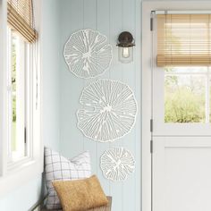 a white door with three decorative wall hangings on it's side and a window in the background