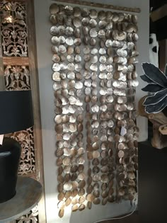 a wall hanging made out of shells in a room with a lamp on the side