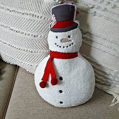 a snowman ornament sitting on top of a couch next to a pillow