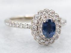 an oval shaped blue sapphire surrounded by white diamonds in a halo setting on a diamond band