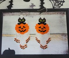 the beaded earrings are decorated with pumpkins and witches on them, while hanging from a black frame