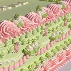 there is a large cake with pink and green frosting