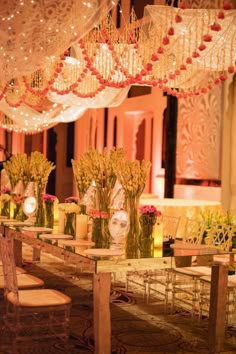 a long table with vases and candles on it in front of a chandelier