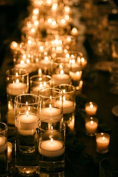 many lit candles are lined up on a table