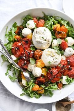 a salad with tomatoes, mozzarella and other toppings in a white bowl