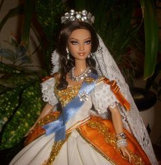 a doll is dressed in an orange and white dress with a tiara on her head